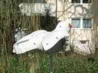 White sparrow sculpture with tiny dark dots and small blue flowers